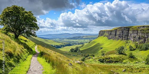 A scenic valley with a winding path, lush green hills, a lone tree, and dramatic cliffs under a vibrant sky filled with clouds.