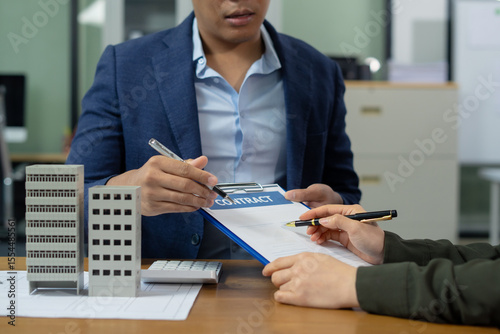 Real estate broker agent presenting and consult to customer to decision making sign insurance form agreement, home model, concerning mortgage loan offer in office.