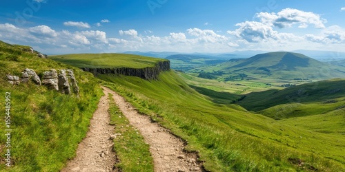 A scenic dirt path winds through lush green hills under a bright blue sky with fluffy clouds in a peaceful countryside landscape.