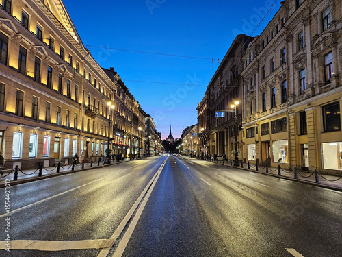 Street with a building on the right side Nevsky Prospect. The street is wet and the sky is blue in Saint-Petersburg