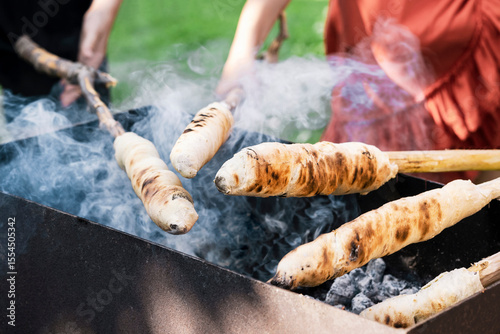 Stockbrot Fire or Stick Bread on Skewer or Stick, Roasted on Flame of Fire. Children prepare Stockbrot Stick Bread over Campfire.  Popular party and camp barbecue food in Germany