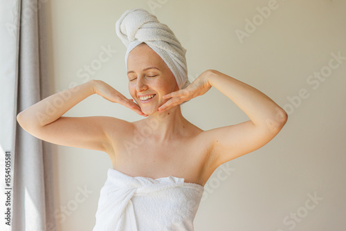 Wallpaper Mural Cheerful young woman wrapped in a white towel smiling with eyes closed, enjoying a peaceful self-care moment at home. Natural beauty, relaxation, and skincare routine concept. Torontodigital.ca