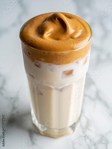 Refreshing dalgona coffee with whipped coffee foam and milk on marble