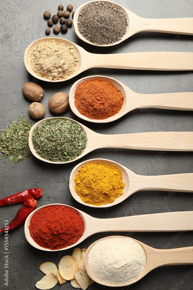 Many different spices in spoons on grey table, flat lay Many different spices in spoons on grey table, flat lay