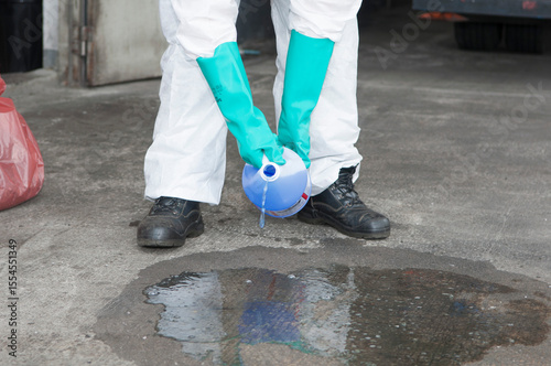 Hazmat Worker Collecting Spilled Liquid in Blue Container