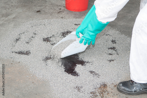 Close-up of Hand Cleaning Thick Industrial Spill with Scraper