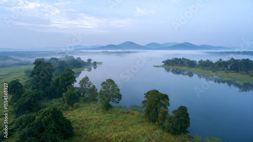 Discover the Serenity of a Misty River Landscape: A Captivating View of Nature's Tranquility Amidst Lush Green Hills and Calm Waters
