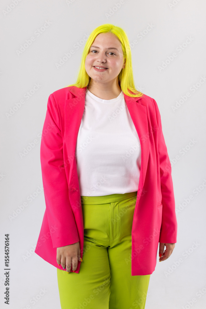 Confident Plus-Size Woman In Pink Blazer And Green Pants On Gray Background Confident Plus-Size Woman In Pink Blazer And Green Pants On Gray Background