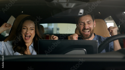 Fotografie Happy couple celebrate buying new car sitting inside salon achieve gesture Cauca