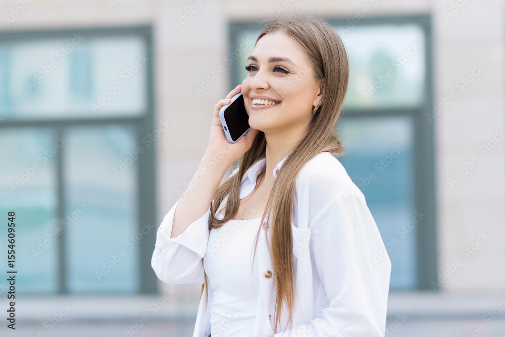 Attractive young woman in casual clothing talking on her mobile phone while walking outdoors in the city. Freelance, business, work, communication Attractive young woman in casual clothing talking on her mobile phone while walking outdoors in the city. Freelance, business, work, communication