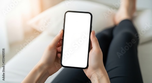 female hand holding black mobile phone with blank white screen, texting using mobile on sofa at home office. background copy space for advertise text, people contact marketing business and technology