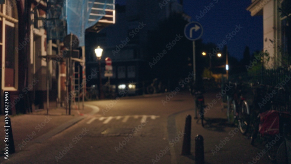 Fototapeta premium Blurry night scene in a european city with bokeh lights, deserted street, and bicycles resting quietly, evoking a serene yet mysterious urban atmosphere.