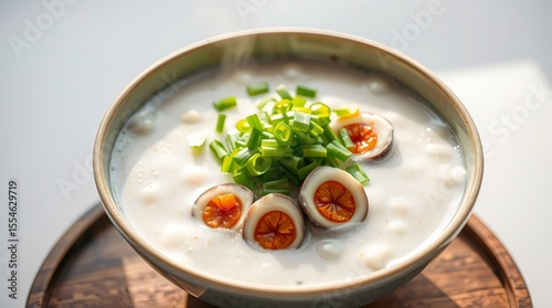 Hot Chinese congee with steam rising, topped with scallions and century egg