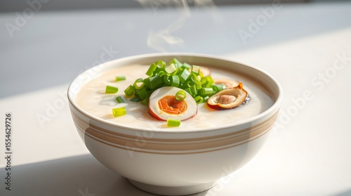 Hot Chinese congee with steam rising, topped with scallions and century egg