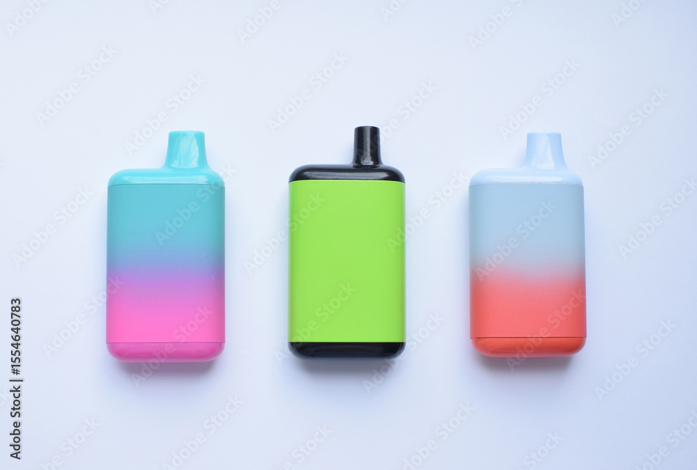Several multi-colored electronic cigarettes lie on a light table. Several multi-colored electronic cigarettes lie on a light table.