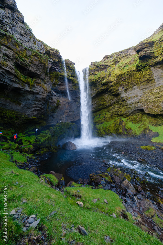 Obraz premium Majestic Kvernufoss waterfall cascading down rocky cliffs in Icelands lush landscape