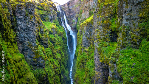 Fotografie Glymur waterfall cascading down lush green cliffs in Icelands scenic landscape