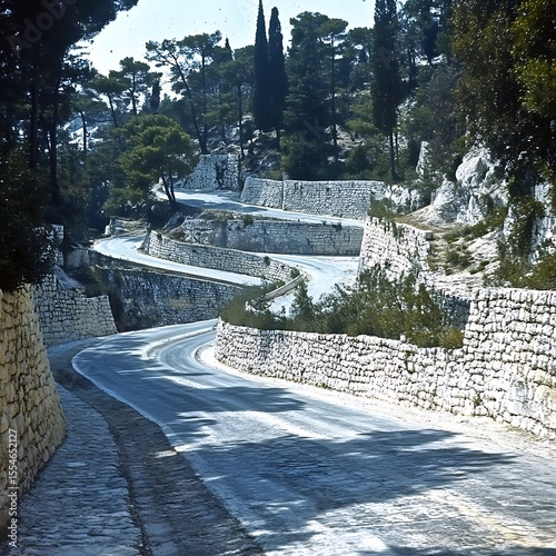 Winding mountain road with stone walls nestled within a dense forest