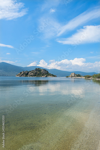 Fototapeta Naklejka Na Ścianę i Meble -  Bafa Lake in sunny weather. Historical castle and city wall ruins in Bafa Lake. Magnificent Bafa Lake view. Muğla, Türkiye.
