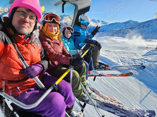 A family of four is posing for a picture on skis. The man is wearing a red jacket and the woman is wearing a purple jacket. The children are wearing blue jackets on ski resort