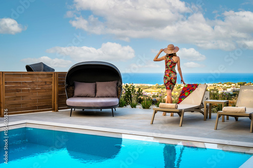 Scenic travel escape with stylish woman enjoying ocean view by poolside. Summer vacation vibes, leisure lifestyle, outdoor luxury, and tranquility define this dreamy travel destination moment.