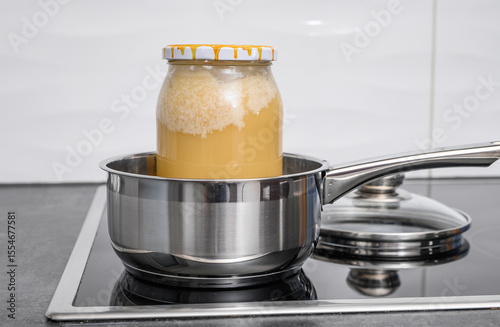 Decrystallization of bee honey, a jar of honey is standing in a pot