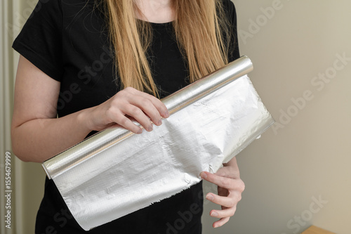 Quadro su tela Woman holding a roll of aluminum foil for baking food