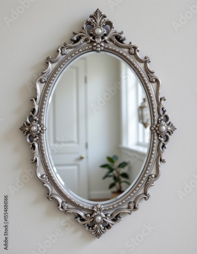 Silver Ornate Oval Mirror with Intricate Floral Frame on White Wall