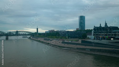 Cityscape of the Rhine river promenade with dramatic cloudscape in Cologne, Germany.