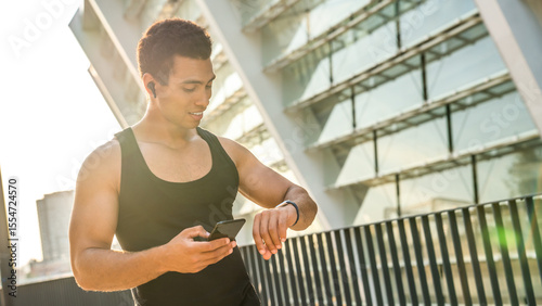 Man, fitness and running with smart watch in city for workout app, exercise or tracking performance. Active, male person or runner checking wristwatch for steps, calories or monitoring heart rate