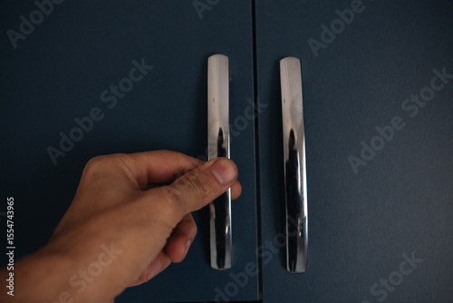 hand holding a black and white metal handle.