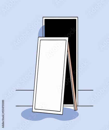 Blank white poster in light wood frame leaning against black frame, creating modern aesthetic