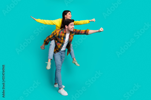Εκτύπωση καμβά Happy young couple posing playfully against a turquoise background, enjoying fun