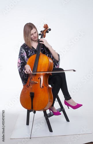 Woman playing cello in studio with white background