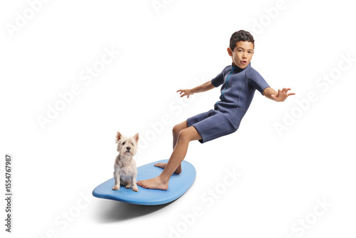 Kid in a wetsuit riding a surfboard with a dog
