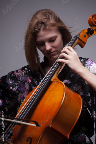 Woman playing cello, wearing floral kimono, close-up.
