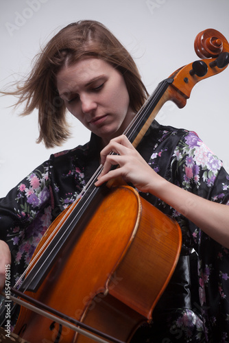 Woman playing cello, wearing floral kimono, close-up.