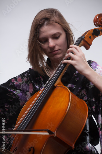 Woman playing cello, wearing floral kimono, close-up.