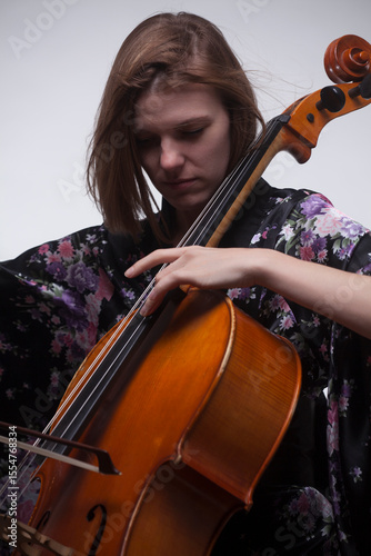 Woman playing cello, wearing floral kimono, close-up.