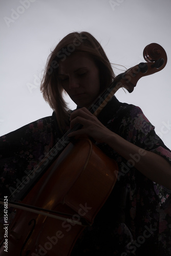 Woman Playing Cello, Silhouette Against Light Background