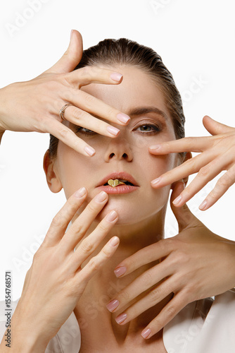 A woman poses with multiple hands framing her face, accentuating her features. The soft lighting highlights her makeup and the artistic arrangement of hands, creating a captivating visual experience.