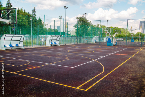 A lilac-colored sports basketball court against the background of houses on a clear sunny day. Playgrounds, toys, sports.