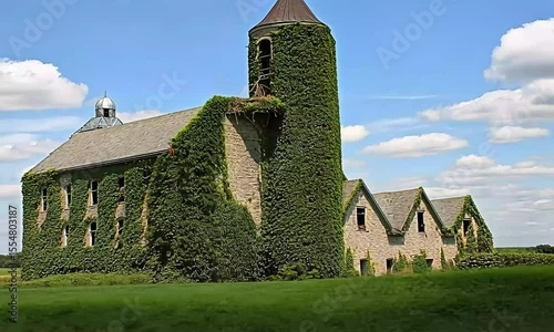Abandoned stone building overgrown with ivy under a partly cloudy sky