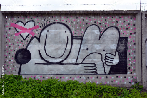 Graffiti, drawn with a white, black, pink spray drawing of a man in the form of a smiley, which hugs a hare with a crossed-out heart.