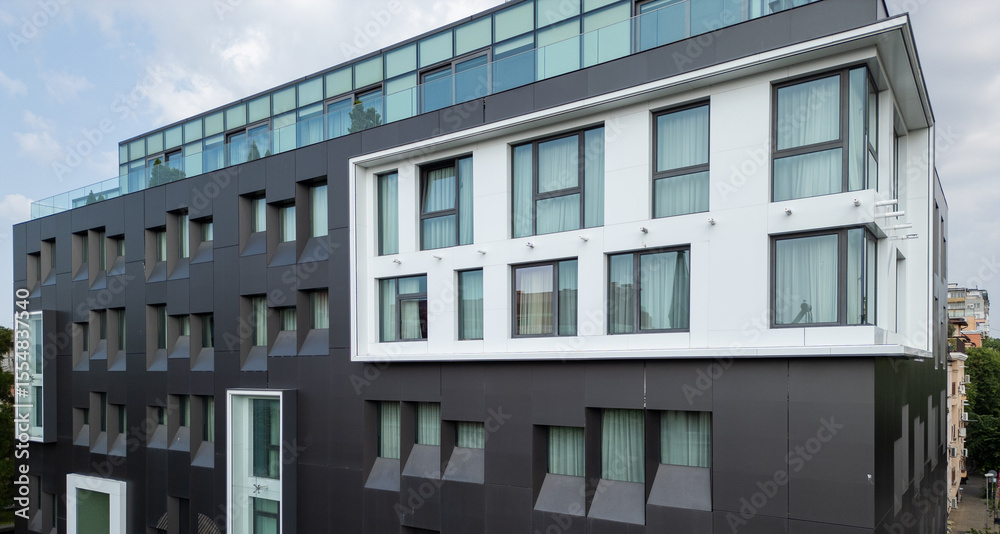 Obraz premium Video of a modern black-and-white building with corner windows and geometric facade. Contemporary urban architecture with clean lines and curtain-covered glass panels