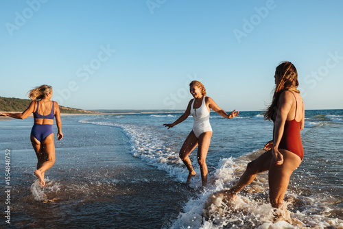 Three friends play joyfully in the ocean at a scenic beach.