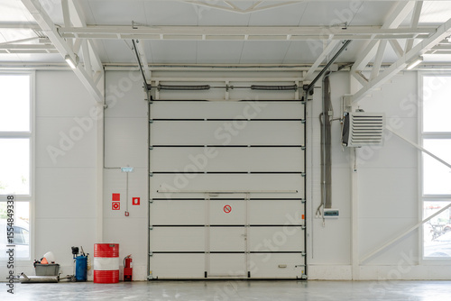 Industrial garage door in modern warehouse interior with fire safety system, HVAC ventilation, engineering infrastructure and storage logistics theme.