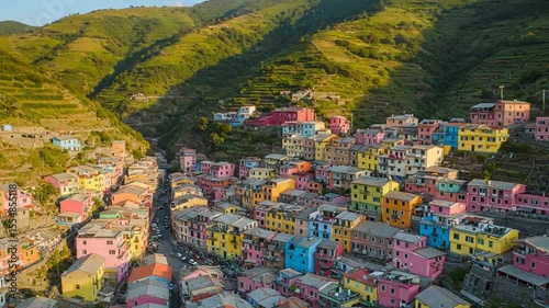Vibrant hillside village with colorful buildings nestled among green mountains at sunset