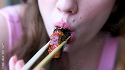 Woman eating Asian sushi rolls with chopsticks close up. smoked eel sushi
