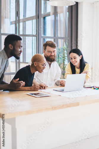 Group of concentrated multiethnic coworkers using laptop at office